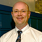 man smiling, wearing glasses, a white shirt and dark tie