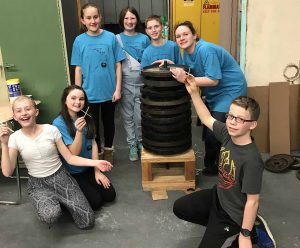 Seven members of the Crispell Middle School Odyssey of the Mind team smile near one of their props.