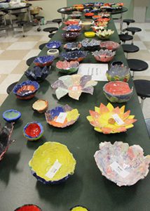 a long table is filled with  handmade bowls