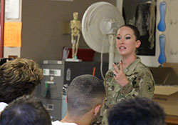 An Army recruiter, with her hair pulled back in a bun and wearing camouflage, talks to the STARS students.