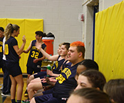 Members of the team high five each other from the bench.