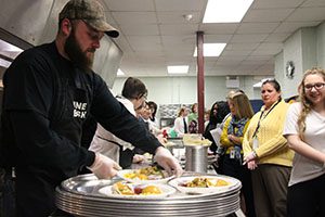 A man puts  a plate containing a turkey dinner on a tray.