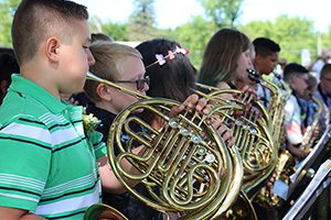 Two boys play French horns in the fifth grade band