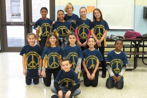 Ten fifth graders wearing their No Place For Hate t-shirts pose with Assistat Principal Colleen Delles.