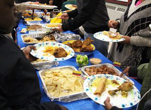 A table filled with different types of food and people filling their plates.
