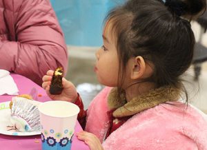 Little girl in pink eating a pice of cake.
