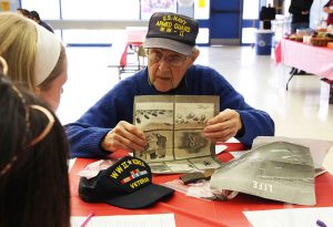 World War II veteran Gene Weinstein holds a copy of Life magazine from the 1940s showing the students.