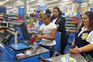 A middle school girl scans a cup at the Walmart register.