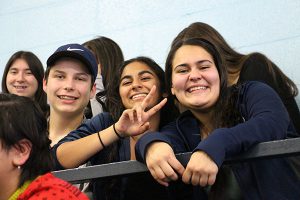 Three students flash smiles and a peace sign at the event