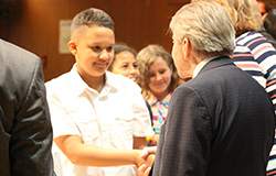 Male student in white short-sleeved shirt shakes the hand of the superintendent