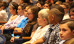 Fifth graders sit in the auditorium seats listening to their principal