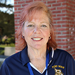 Woman with red hair smiling, wearing blue Pine Bush Schools shirt