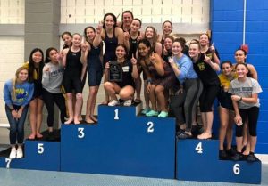 girls swim team crowd the podium