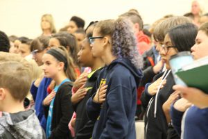 students stand with hands over heard to pledge allegiance