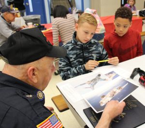 Veteran shows two students photos of airplanes