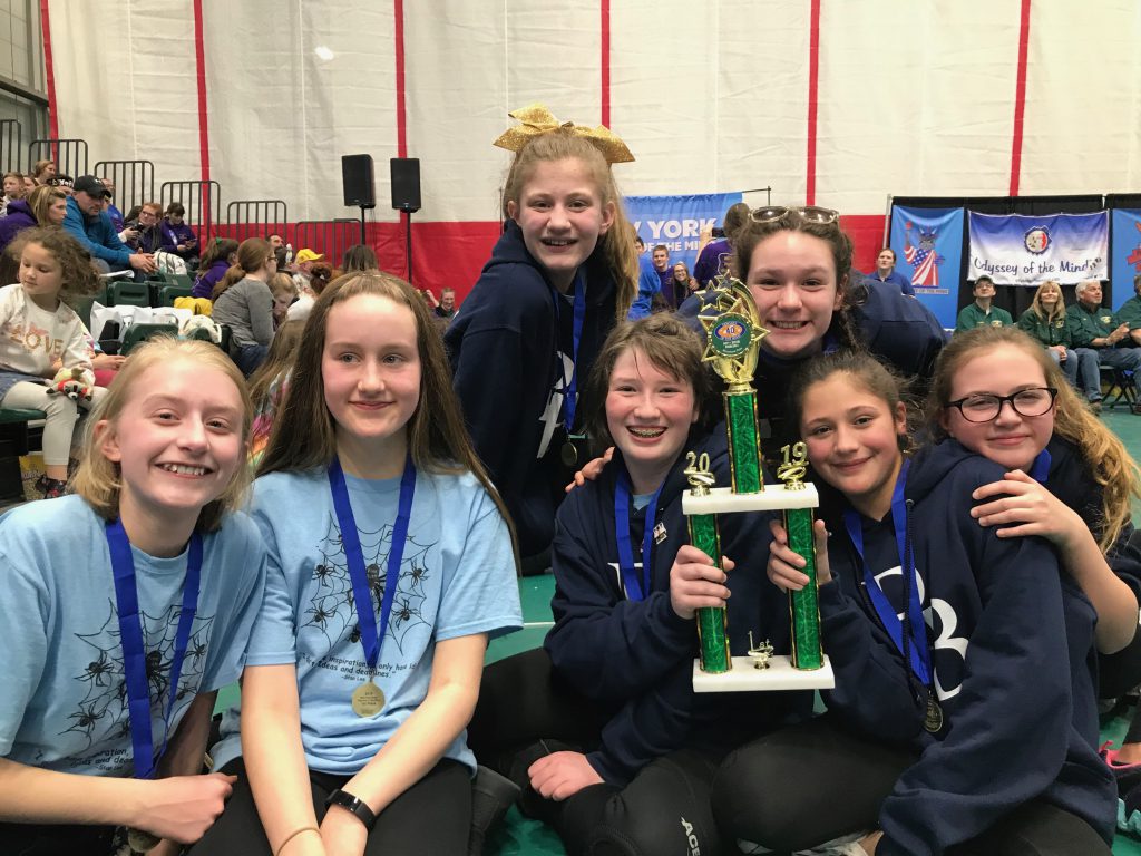 Seven middle school students all girls smiling broadly and holding their trophy