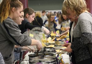 Students on the left ladle out soup to  adults 