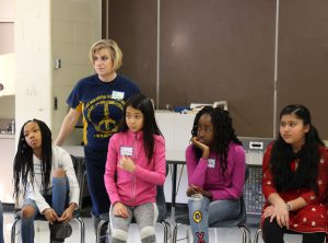 One adult and four girls listen attentively as the speaker talks