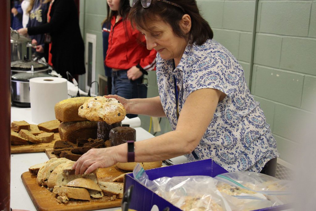 Woman with short brown hair puts different varieties of bread on the platter.