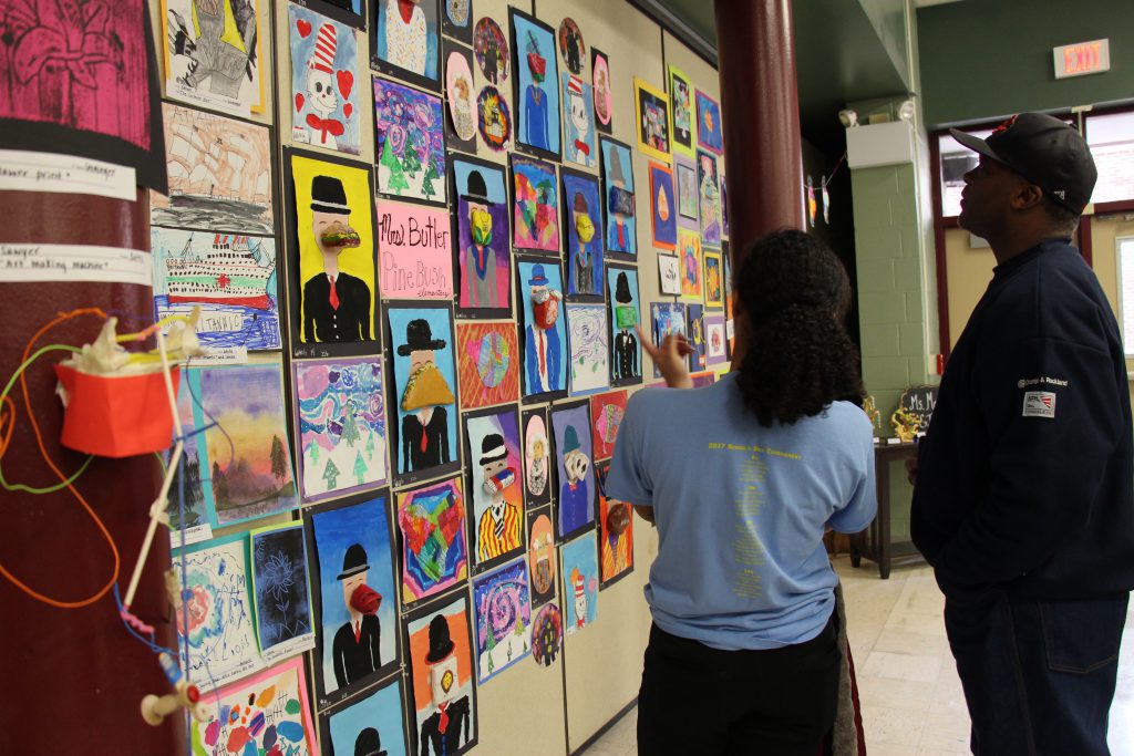 A parent and a student look at a wall of art