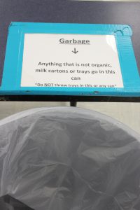 The top of a garbage can with a sign on it explaining what goes in there