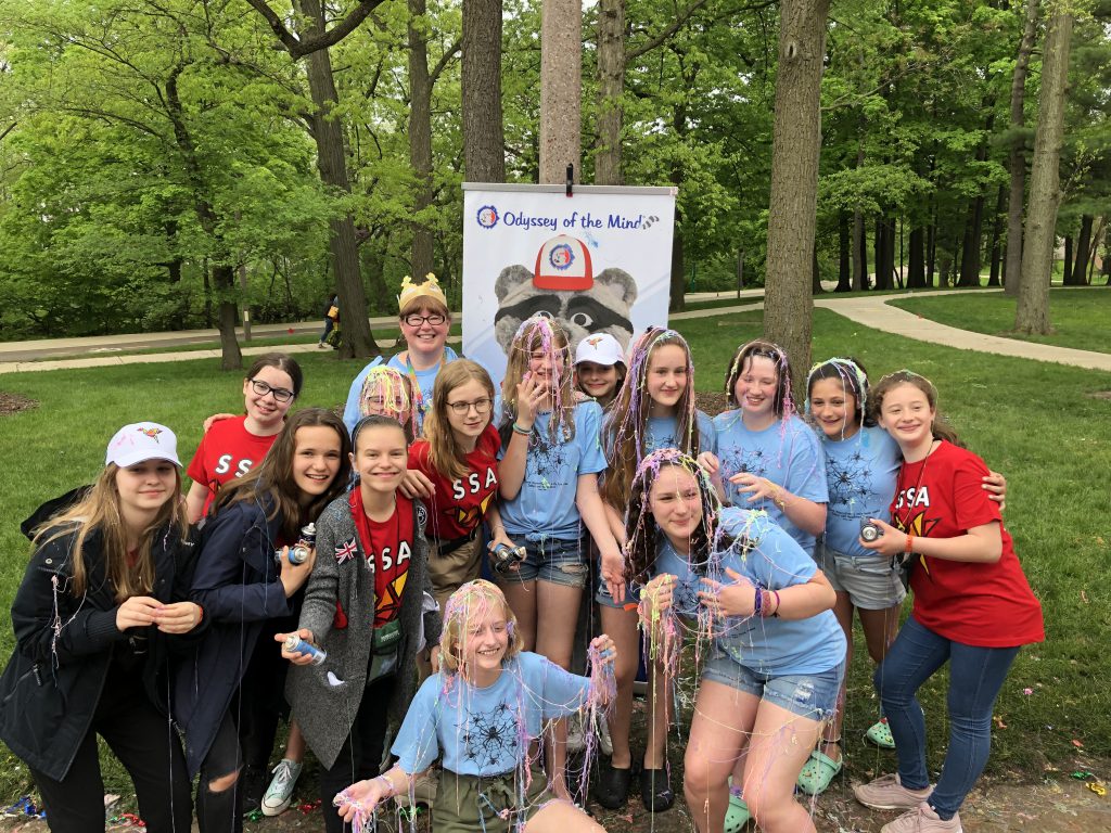 Group of 15 middle school girls, some with silly string on them, all smiling.