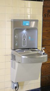 A stainless steel water fountain with a water bottle filling area.