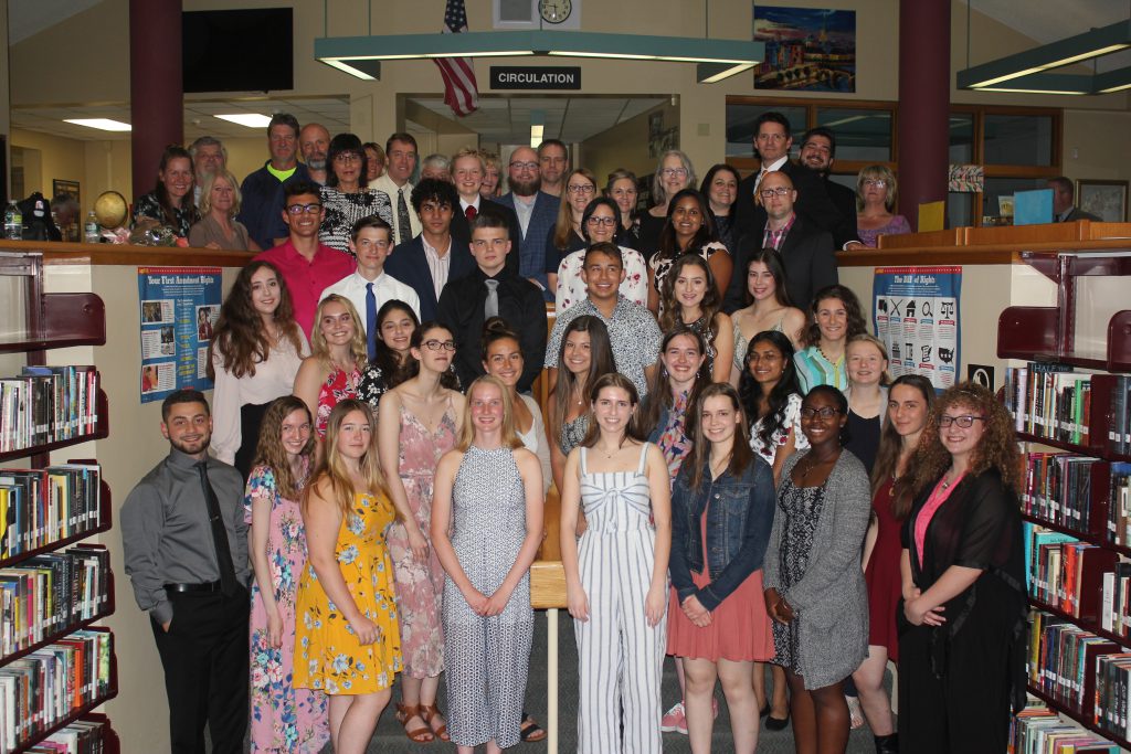 Nearly 30 high school seniors and their mentors stand on the step of the library