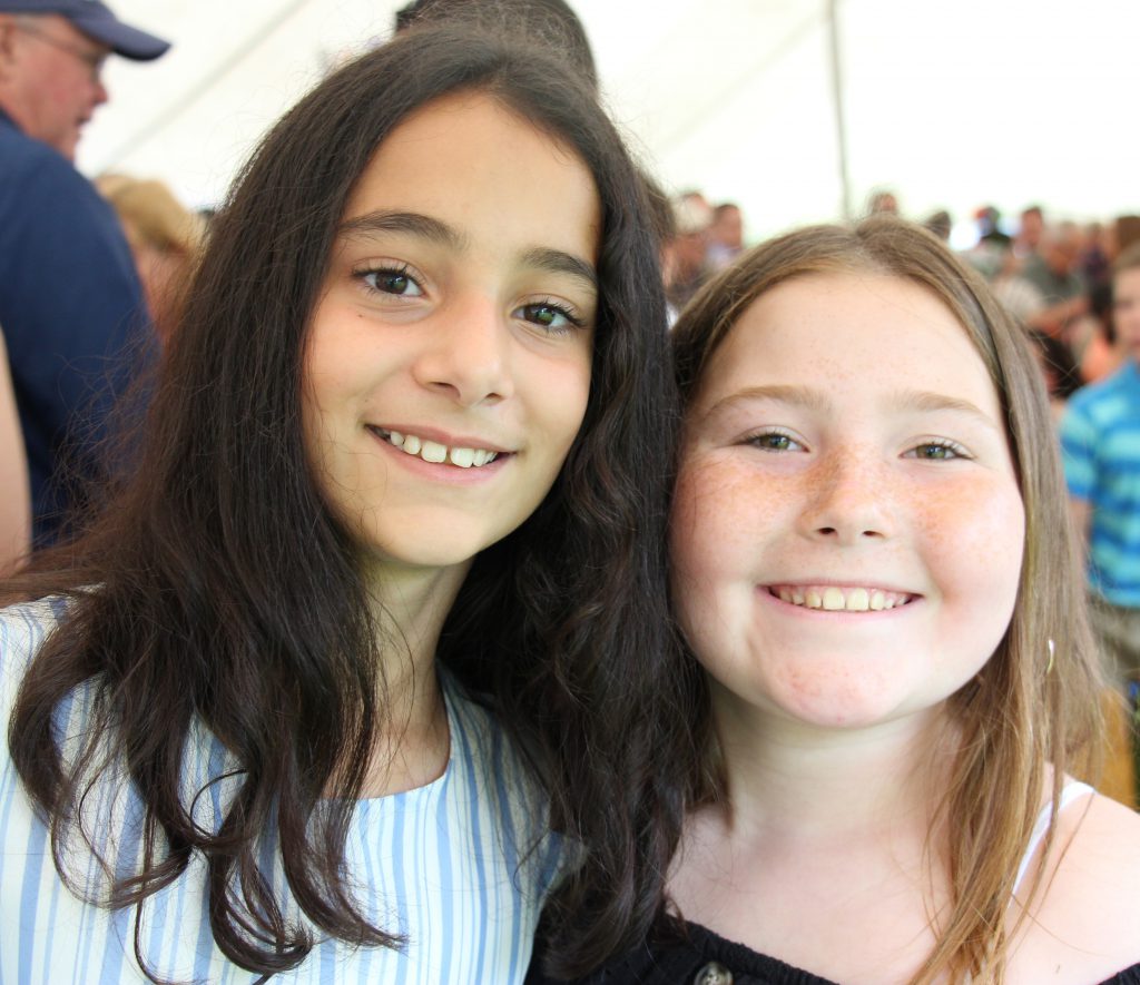 A girl with long dark hair and another with long blonde hair smile after the ceremony