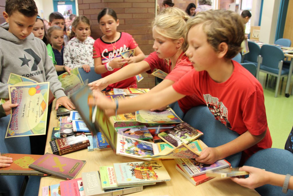 Students line up and wait their turn to choose a book from the table