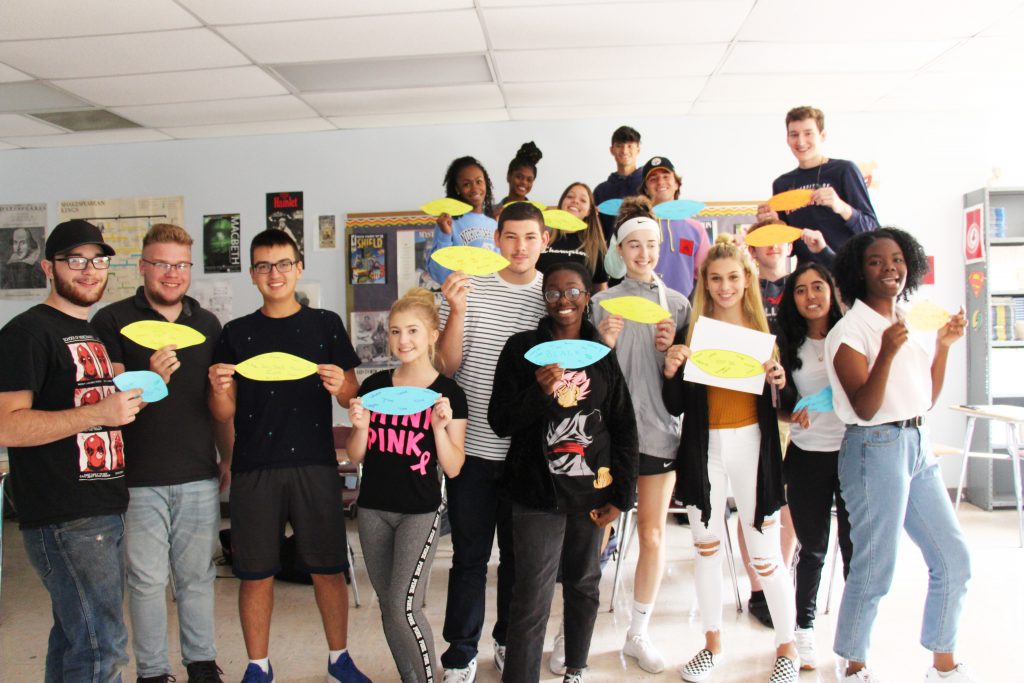 A group of 17 high school seniors hold their paper leafs, which contain the words they use to describe themselves