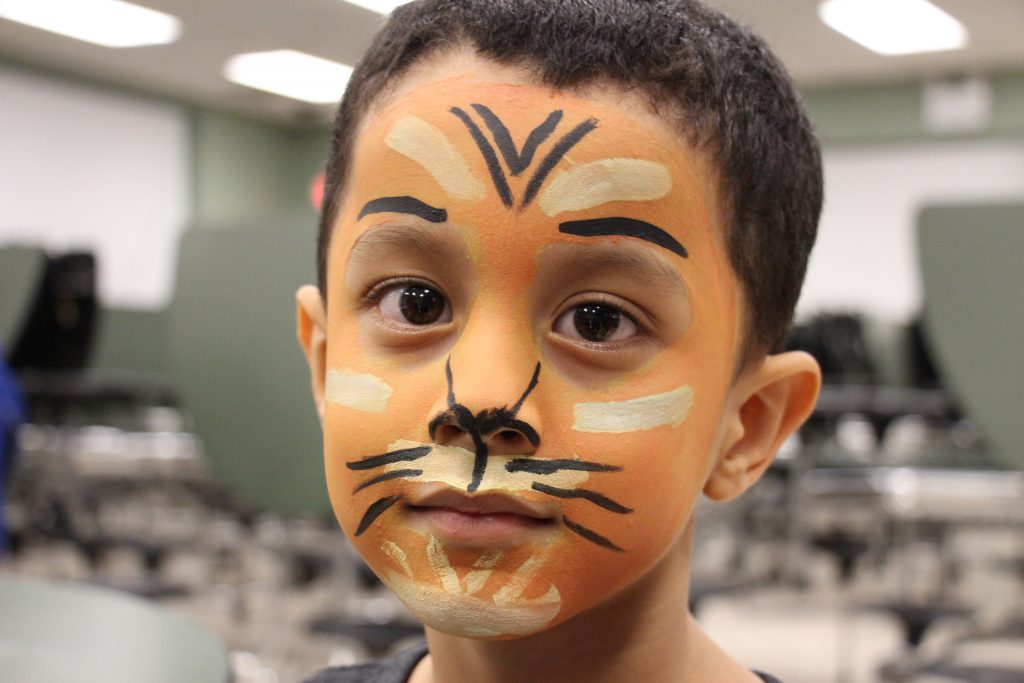 A young boy with his face painted as a tiger.