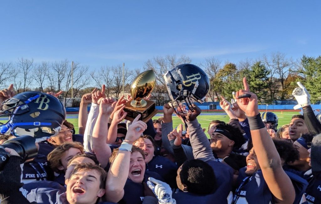 Football players cheer and hold up a gold trophy and helmets