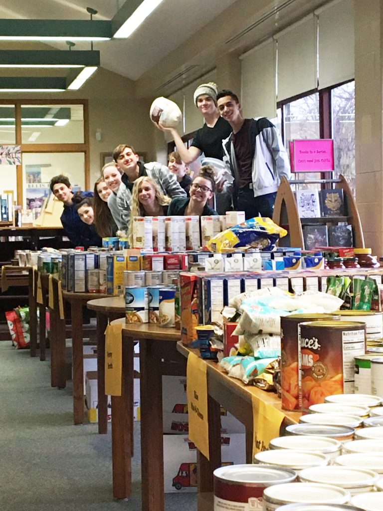 High School students with tables of donated non-perishable food items and some turkeys