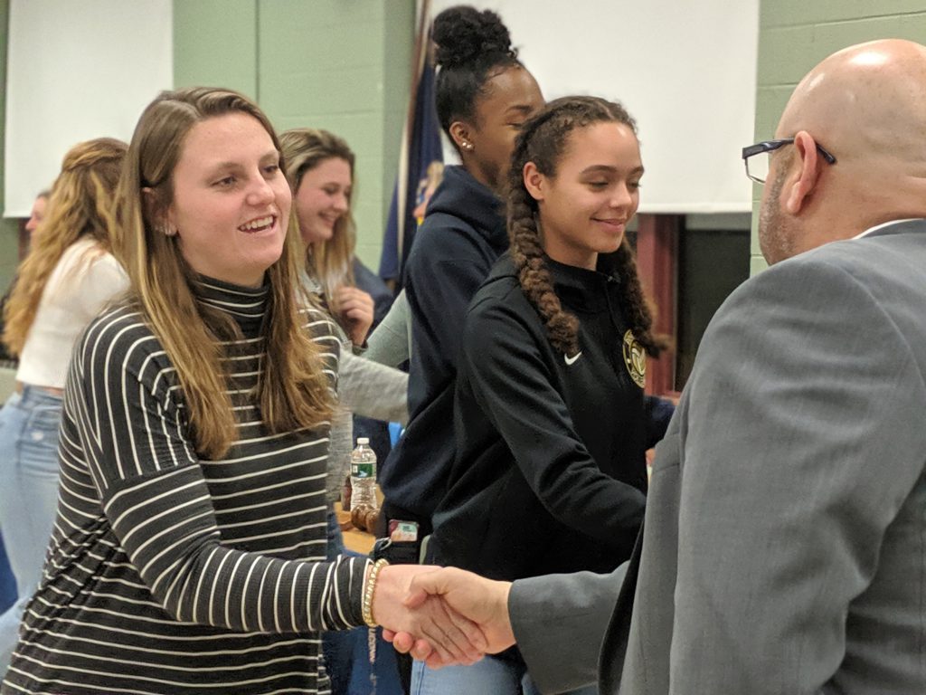 Two young women shake hands with two adults.