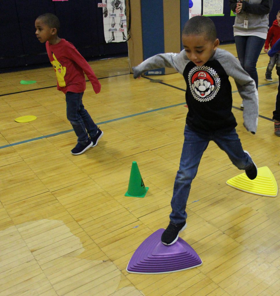 An elementary school boy jumps from one triangle stepping stone to the next one.