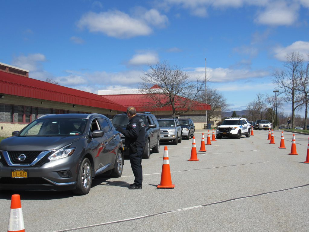 blue skies, white clouds and a line of cars waiting in front of tPine Bush High School 