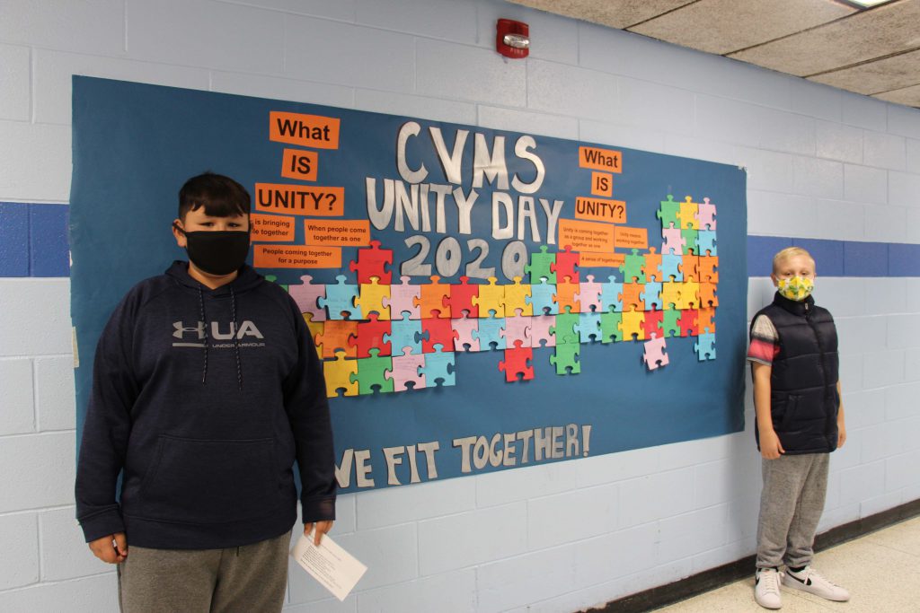 Two middle school students wearing masks stand on each end of the large bulletin board that says CVMS Unity Day 2020