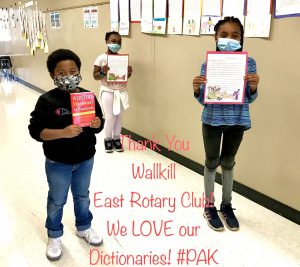 Three third-grade students hold either letters written to the Rotary or a dictionary.