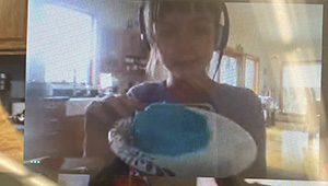 On a computer screen, a girl holds her blue bowl.
