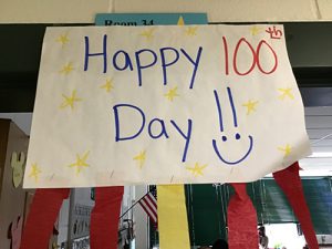 Large colorful sign that says Happy 100th Day with a smiley face.