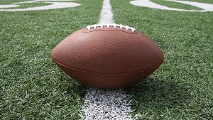 A football sitting on a white line with green grass around it.