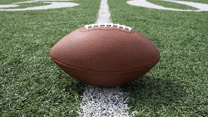 A football sitting on a white line with green grass around it.