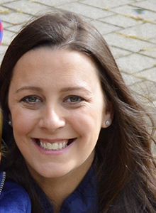 A womanwith long brown hair smiles.