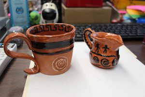 Two small pieces of pottery. They are orange with black stripes and markings.
