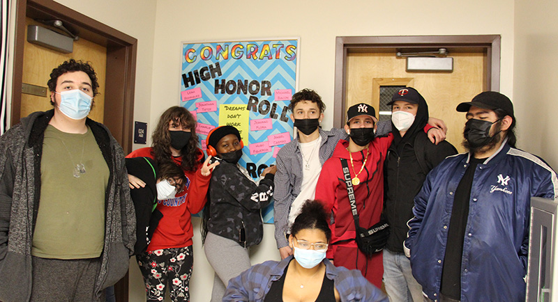 A group of nine high school students stand together in front of a board that says High Honor Roll.