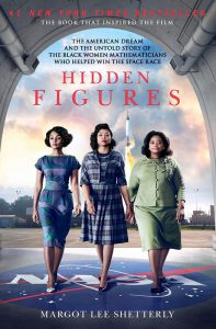 Three women dressed in 1950s-era suits walk together. The words Hidden Figures is above them. 