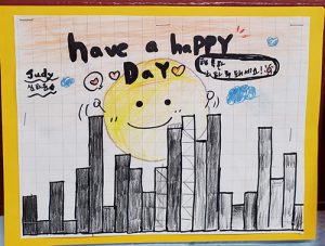 A drawing of different height lines, looking like a skyline. There is a large sun rising and above it says Have a Happy Day.