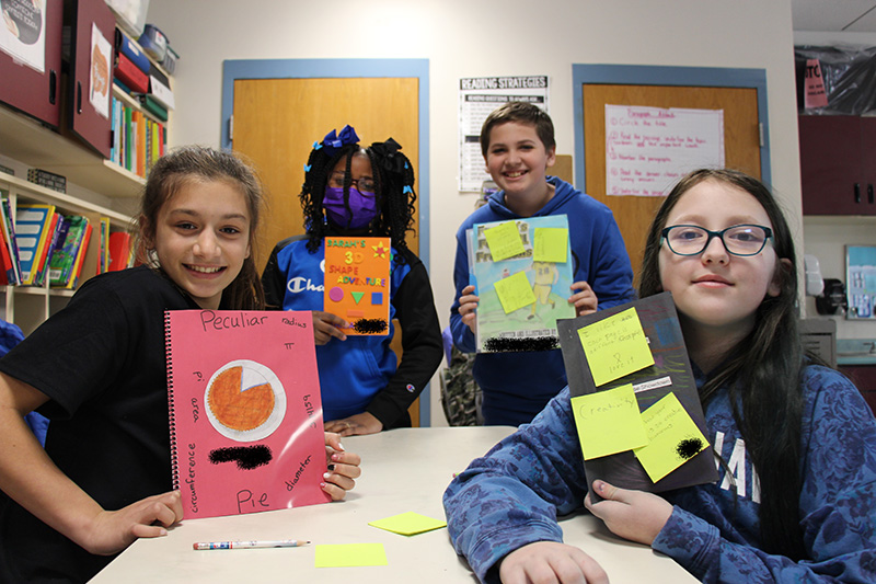 A group of four fifth grade students holding up their homemade books.