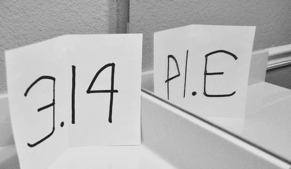 the numbers 3.14 on a piece of paper and shown in a mirror where it is reflected as the word pie.